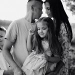 A serene black and white portrait of a family standing by a lake.